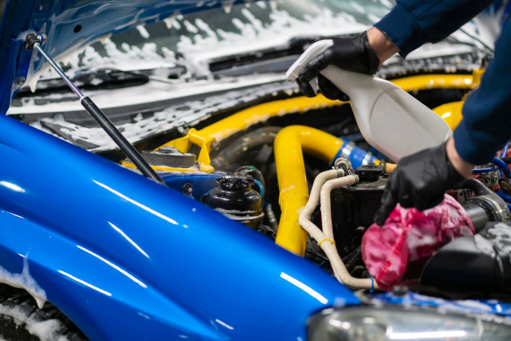 a male detailer with brush cleaning the engine bay
