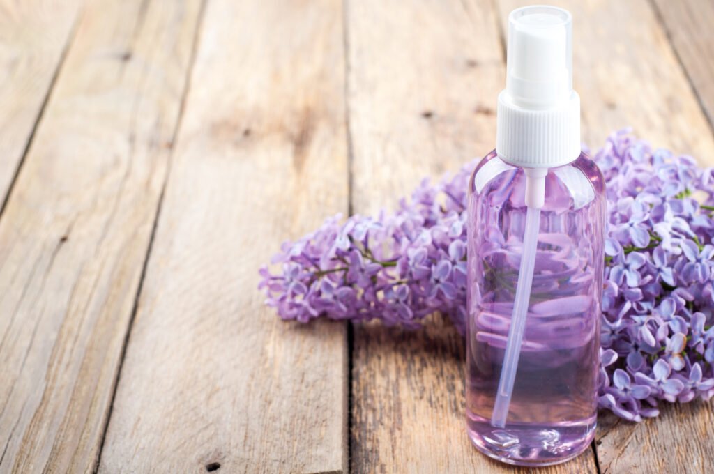 Blossoming lilac and bottle of essential oil or flower hydrolat.
