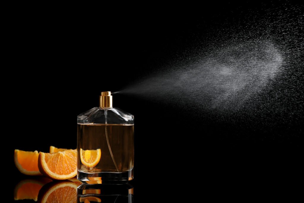 Spraying bottle of perfume and slices of citrus fruit on black background