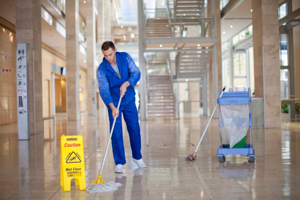 Male cleaner mopping in office atrium